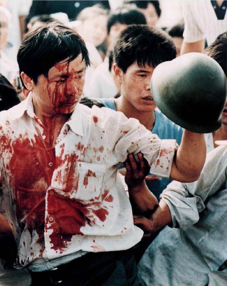 Κίνα - 1989: Η εξέγερση στην πλατεία Τιενανμέν. Τραυματισμένος διαδηλωτής κρατά το κράνος ενός κινέζου στρατιώτη, μετά από τις βίαιες συγκρούσεις με τις στρατιωτικές δυνάμεις, κατά τη διάρκεια των φιλοδημοκρατικών διαδηλώσεων στην πλατεία Τιενανμέν του Πεκίνου, στις 4 Ιουνίου 1989.