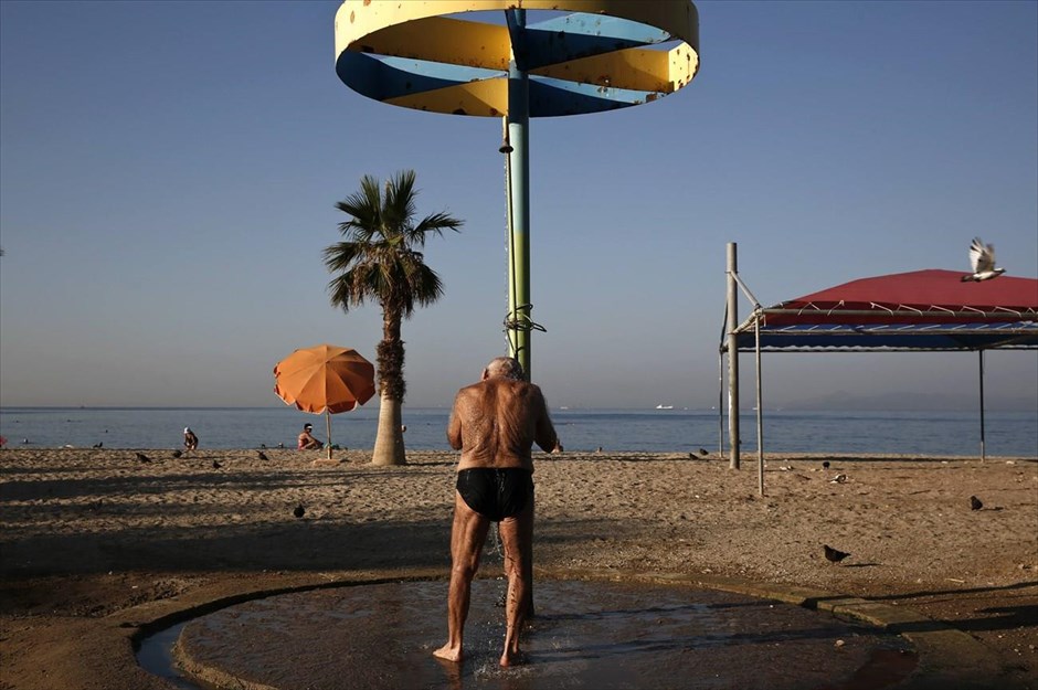Καλοκαιρινή απόδραση σε παραλία της Αθήνας. Ένας άντρας κάνει ντούς σε μία παραλία, στα δυτικά προάστια της Αθήνας.