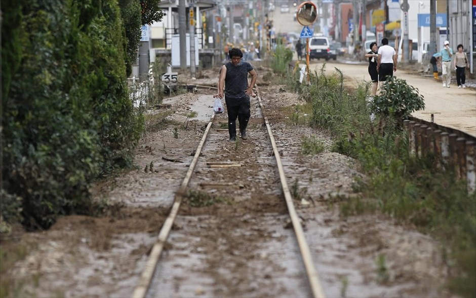 Κατολισθήσεις στη Χιροσίμα 1. Ένας κάτοικος της Χιροσίμα περπατά πάνω στις καλυμμένες από τη λάσπη σιδηροδρομικές γραμμές.