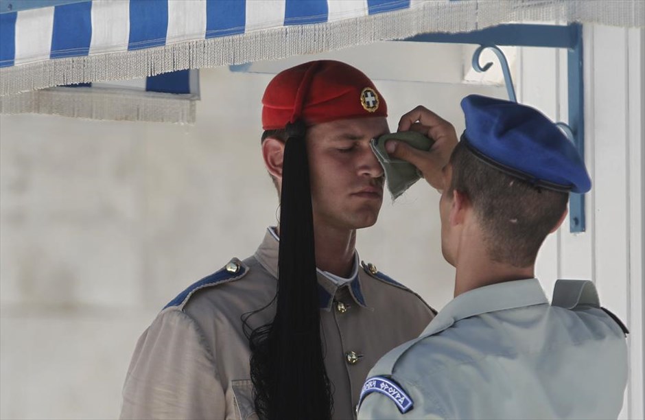 Υψηλές θερμοκρασίες στην Αττική. Ένας άνδρας της προεδρικής φρουράς (δεξιά) σκουπίζει τον ιδρώτα από το πρόσωπο εύζωνα μπροστά από τη Βουλή. Νέα άνοδο σημειώνει η θερμοκρασία το Σαββατοκύριακο, κυρίως στα κεντρικά και νότια της χώρας.