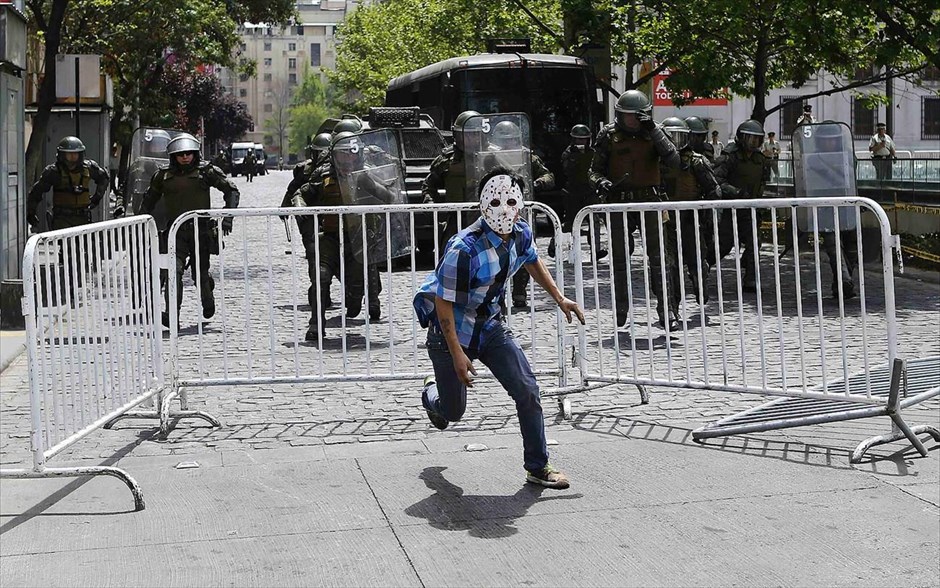 Διαδηλώσεις κατά της Ημέρας του Κολόμβου στη Χιλή. Ινδιάνος ακτιβιστής της φυλής Μαπούτσε τρέχει να ξεφυγει από αστυνομικούς, κατά τη διάρκεια διαδήλωσης εναντίον της Ημέρας του Κολόμβου, στο Σαντιάγκο. Η φετινή χρονιά σηματοδοτεί την 522η επέτειο της άφιξης του Χριστόφορου Κολόμβου στην Αμερική. Πολλοί ιθαγενείς στη Λατινική Αμερική θεωρούν ότι η ημέρα αυτή έφερε στην ήπειρο τη δουλεία, την αποικιοκρατία και τη γενοκτονία από την Ευρώπη.