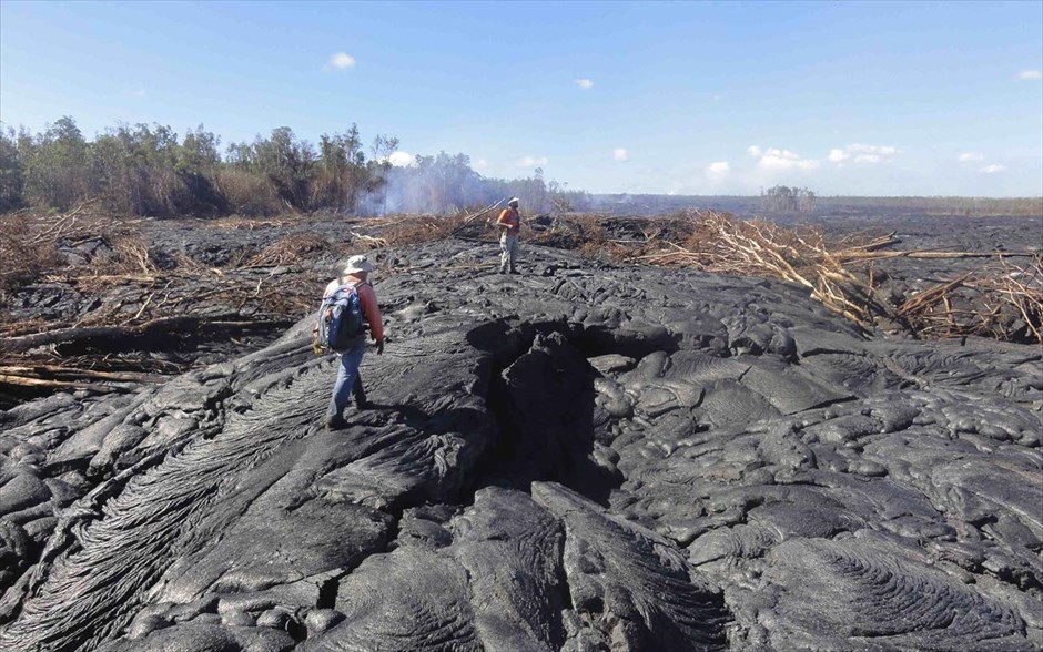 Ποτάμι λάβας στη Χαβάη. Γεωλόγοι του Ηφαιστειολογικού Παρατηρητηρίου της Χαβάης περπατούν πάνω σε μία επιφάνεια ροής λάβας, κοντά στην Παχόα.