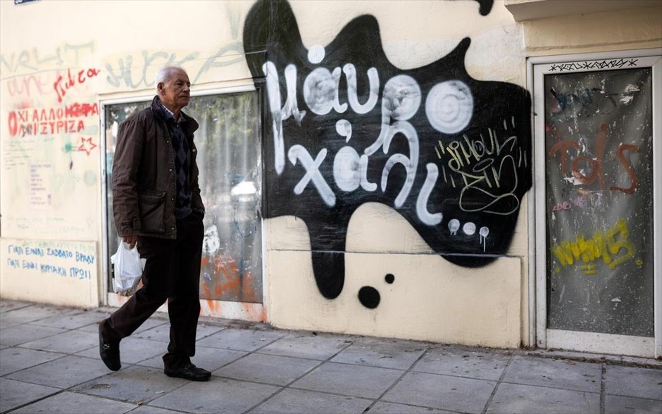 Στιγμιότυπο από δρόμο της Θεσσαλονίκης. &nbsp;Ένας άνδρας περνά μπροστά από ένα γκράφιτι σε τοίχο της Θεσσαλονίκης.