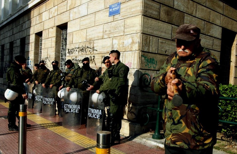 Μπροστά από τα ΜΑΤ. Ηλικιωμένος άντρας αστειεύεται με το μπαστούνι του μπροστά από άνδρες των ΜΑΤ που βρίσκονται έξω από το την πρυτανεία του Πανεπιστημίου Αθηνών. Το Σάββατο, ενώ βρισκόταν σε εξέλιξη η συνεδρίαση της Συγκλήτου του ΕΚΠΑ, μικρή ομάδα φοιτητών συγκεντρώθηκε έξω από το κεντρικό κτήριο του ιδρύματος ζητώντας να εισέλθει σε αυτό. Η είσοδος δεν τους επετράπη και έπειτα από μικροένταση οι φοιτητές αποχώρησαν.