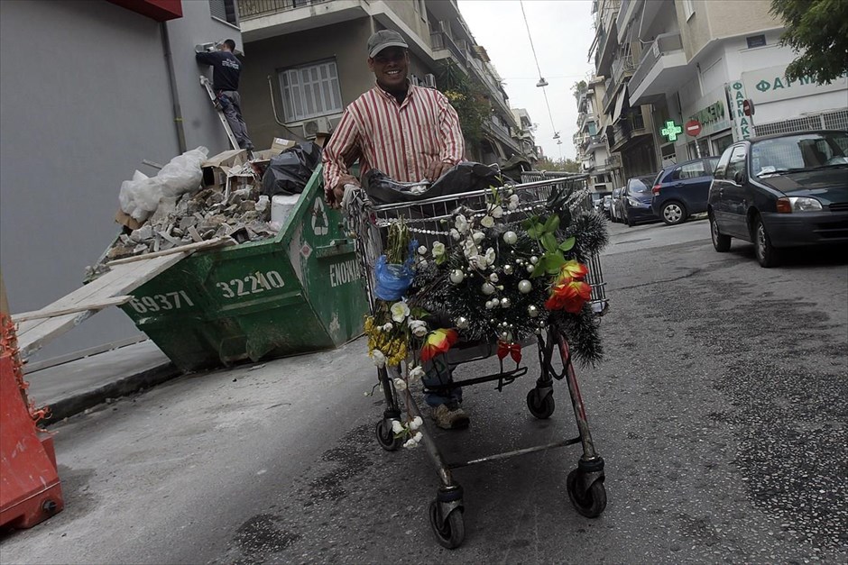 Στιγμιότυπο από δρόμο της Αθήνας. Άντρας που μαζεύει ανακυκλώσιμα υλικά από τους δρόμους της Αθήνας επιδεικνύει με χαμόγελο στο φωτογραφικό φακό το καρότσι του, το οποίο έχει διακοσμήσει με χριστουγεννιάτικα στολίδια.