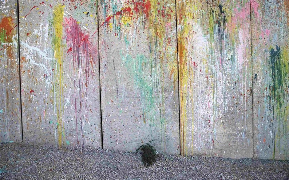 Τα τείχη που χωρίζουν τον κόσμο - Δυτική Όχθη. Μπογιά σε τμήμα του διαχωριστικού τείχους στην πόλη Άμπου Ντις της Δυτικής Όχθης. Το τείχος που χωρίζει το Ισραήλ από τη Δυτική Όχθη αποτελείται από φράχτες, αγκαθωτό συρματόπλεγμα και πλάκες τσιμέντου. Η ισραηλινή κυβέρνηση ενέκρινε την ανέγερσή του τείχους το 2002 και σύμφωνα με τα Ηνωμένα Έθνη έχει ολοκληρωθεί σχεδόν το 60% του αρχικού σχεδιασμού. Το Διεθνές Δικαστήριο της Χάγης το έκρινε παράνομο το 2004, όμως το Ισραήλ το διατηρεί και το ενισχύει με το επιχείρημα ότι αποτελεί προστασία από τις επιθέσεις των Παλαιστινίων.