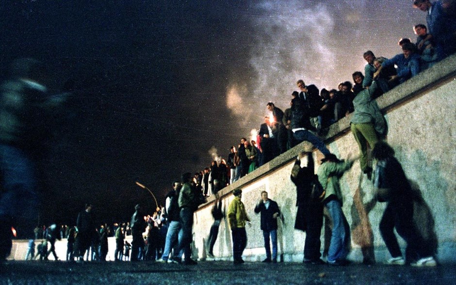 Η πτώση του Τείχους του Βερολίνου. Πολίτες από την Ανατολική Γερμανία σκαρφαλώνουν στο Τείχος του Βερολίνου στην Πύλη του Βραδεμβούργου, μετά την ανακοίνωση για το άνοιγμα των συνόρων της Ανατολικής Γερμανίας στο Βερολίνο (φωτογραφία αρχείου, 9 Νοεμβρίου 1989).