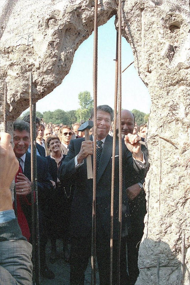 Η πτώση του Τείχους του Βερολίνου. Ο πρώην πρόεδρος των ΗΠΑ Ρόναλντ Ρήγκαν, φωτογραφίζεται στο τείχος του Βερολίνου με ένα σφυρί, κοντά στην Πύλη του Βραδεμβούργου, κατά τη διάρκεια επίσκεψής του στη Γερμανία (φωτογραφία αρχείου, 12 Σεπτεμβρίου 1990).
