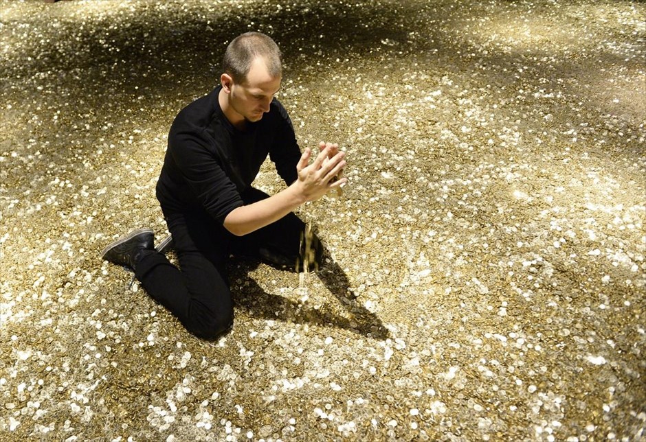 «Κολυμπώντας» στο χρυσάφι. Επισκέπτης της έκθεσης «Χρήμα: πέρα από το καλό και το κακό» παίζει με κέρματα στο Stapfer Haus στο Λέντζμπουργκ της Ελβετίας. 