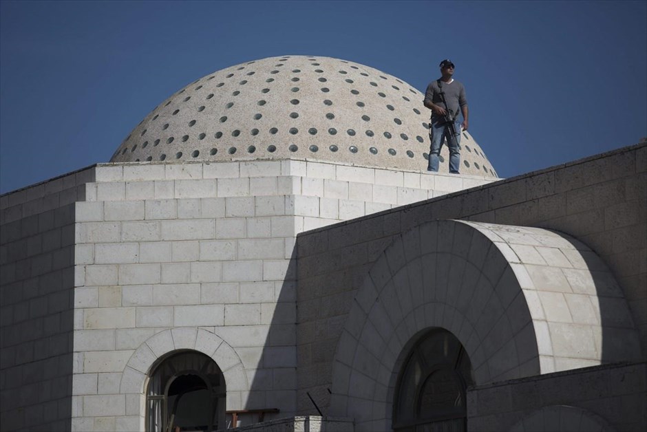 Αιματηρή επίθεση σε συναγωγή της Ιερουσαλήμ. Αστυνομικός στέκεται στην οροφή της συναγωγής.