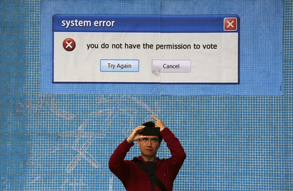 «System error». Ένας άντρας βγάζει φωτογραφία μπροστά από μία καλλιτεχνική τοιχογραφία των φιλοδημοκρατικών διαδηλωτών του Occupy Central, στο Ναυαρχείο, στο Χονγκ Κονγκ. Οι αρχές του κάλεσαν τους διαδηλωτές να εκκενώσουν τον κύριο χώρο που έχουν καταλάβει κοντά στην έδρα της κυβέρνησης, καθώς δεν μπορούν να εγγυηθούν ότι δεν θα υπάρξουν συγκρούσεις, κατά την εκκαθάριση της περιοχής από την αστυνομία την Πέμπτη.