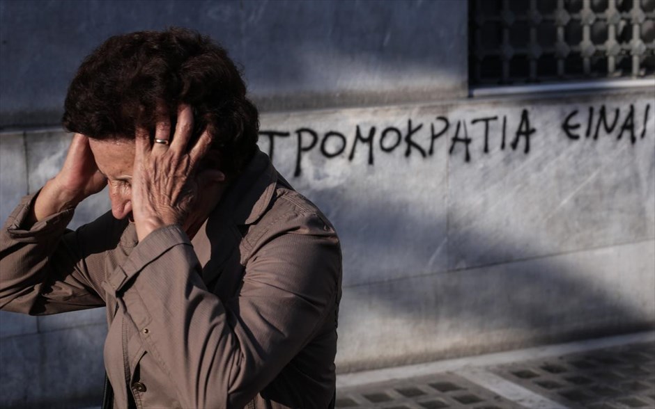 POY2014 - ΦΤΧ - Οκτώβριος. Μια γυναίκα περνά μπροστά από ένα σύνθημα γραμμένο σε τοίχο, στην Αθήνα, 14 Οκτωβρίου 2014.