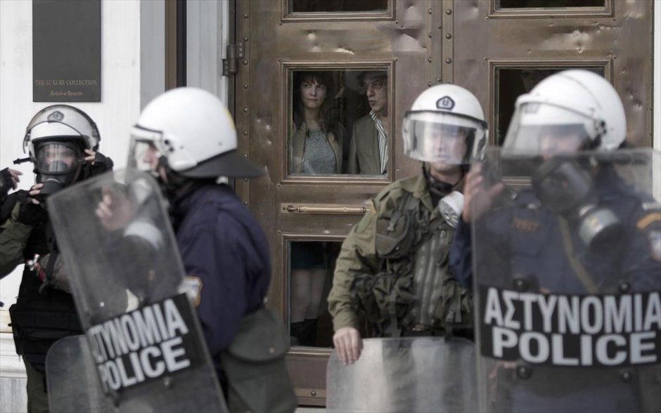 POY2014 - ΦΤΧ - Νοέμβριος. Τουρίστες κοιτάζουν μέσα από το ξενοδοχείο Μ. Βρετανία, τους άνδρες των ΜΑΤ που βρίσκονται παραταγμένοι έξω, κατά τη διάρκεια πορείας φοιτητών για την 41η επέτειο της εξέγερσης του Πολυτεχνείου, τη Δευτέρα 17 Νοεμβρίου 2014. Με την καθιερωμένη πορεία προς την αμερικανική πρεσβεία ολοκληρώθηκαν οι εκδηλώσεις για την επέτειο του Πολυτεχνείου. Επί ποδός βρέθηκαν περίπου 7.000 αστυνομικοί.