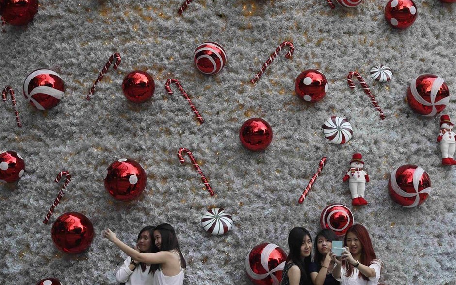 Χριστουγεννιάτικο κλίμα στη Σιγκαπούρη. Γυναίκες τραβούν "selfies" μπροστά από ένα χριστουγεννιάτικο δέντρο, έξω από ένα εμπορικό κέντρο στην οδό Όρτσαρντ, στη Σιγκαπούρη.