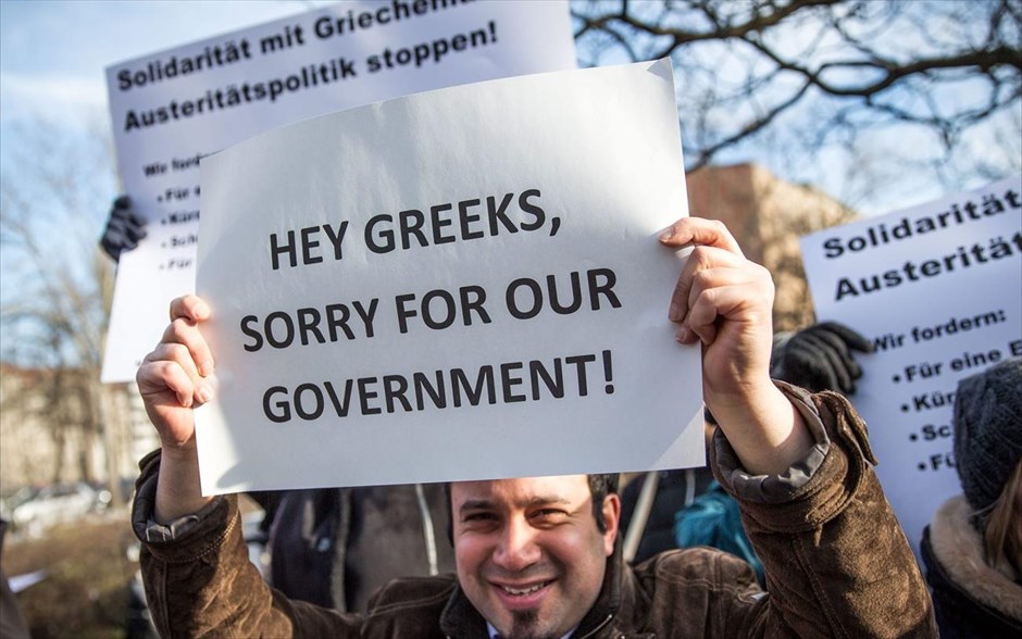 Συγκέντρωση υπέρ της Ελλάδας έξω από το γερμανικό ΥΠΟΙΚ. Ένας διαδηλωτής υψώνει πλακάτ στο οποίο αναγράφεται η φράση: «Έλληνες, συγγνώμη για την κυβέρνησή μας! μπροστά από το γερμανικό υπουργείο Οικονομικών στο Βερολίνο. Υπό το σκηνικό σύγκρουσης που προδιαγράφουν οι πιέσεις του Βερολίνου για τήρηση των υποχρεώσεων, όπως αυτές αποτυπώνονται στο γερμανικό έγγραφο το οποίο δημοσίευσε το Reuters, συναντώνται αυτή την ώρα ο υπουργός Οικονομικών Γιάνης Βαρουφάκης και ο Γερμανός ομόλογός του, Βόλφγκανγκ Σόιμπλε.