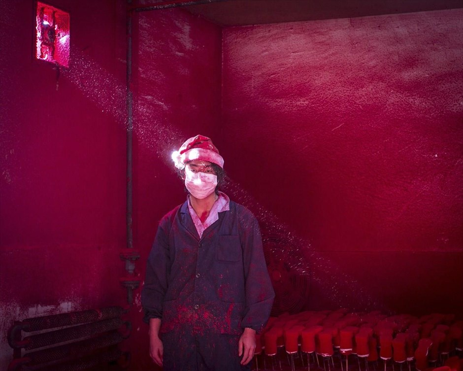 World Press Photo 2015. Ο Κινέζος Ronghui Chen από το «City Express» κέρδισε το δεύτερο βραβείο στην κατηγορία «Contemporary Issues, Singles». Στη φωτογραφία, με ημερομηνία 6 Δεκεμβρίου 2014, απεικονίζεται ένας 19χρονος Κινέζος εργάτης που φορά μάσκα και καπέλο του Αγίου Βασίλη, να στέκεται δίπλα σε χριστουγεννιάτικα στολίδια, τα οποία βάφτηκαν κόκκινα και στεγνώνονται, σε εργοστάσιο της Κίνας.&nbsp;