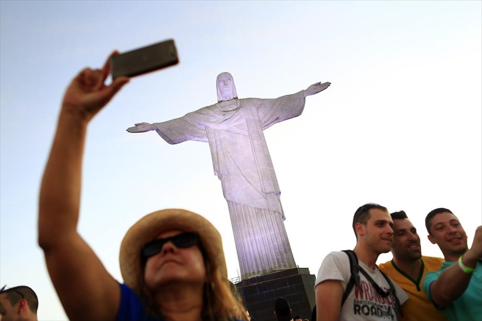 Η εποχή των «selfies». Τουρίστες που επισκέπτονται τη Βραζιλία με αφορμή το Παγκόσμιο Κύπελλο του Ιουνίου 2014, φωτογραφίζονται με φόντο το διάσημο άγαλμα του Χριστού Λυτρωτή στο Ρίο ντε Τζανέιρο.&nbsp;