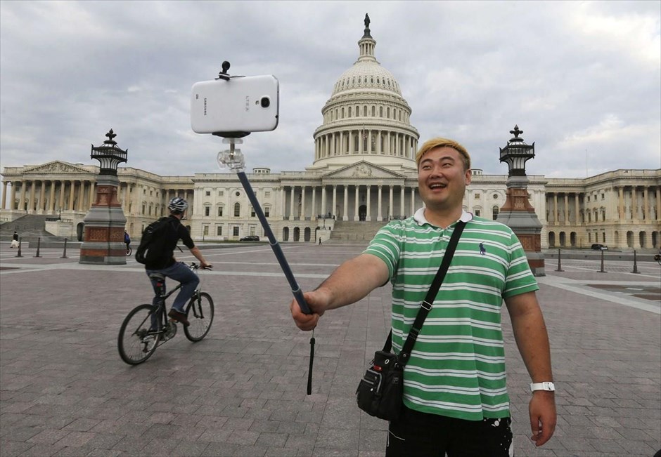 Η εποχή των «selfies». Τουρίστας από τη Νότια Κορέα χρησιμοποιεί ένα μπαστούνι για «selfies» έξω από το Καπιτώλιο την περίοδο της διακοπής λειτουργίας της αμερικανικής κυβέρνησης το 2013.