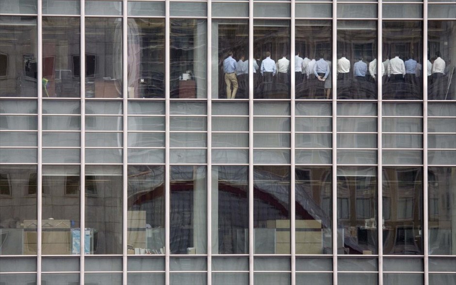 Αφιέρωμα - Reuters 30. Υπάλληλοι της Lehman Brothers στέκονται στην αίθουσα συνεδριάσεων στα γραφεία της επιχείρησης, στην περιοχή Κάναρι Γουάρφ στο Λονδίνο, στις 11 Σεπτεμβρίου 2008.Ο φωτογράφος Kevin Coombs διηγείται: «Είναι μια πολύ απλή ιστορία. Η φωτογραφία τραβήχτηκε από τον 4ο όροφο των γραφείων μας, απέναντι από την Lehman Brothers. Ενώ δούλευα, πρόσεξα 3-4 από τους δημοσιογράφους μας να κοιτάνε έξω από το παράθυρο, κάτι αρκετά περίεργο για το πολυάσχολο γραφείο μας. Τότε άρπαξα την φωτογραφική μου μηχανή και έτρεξα να δω τι συμβαίνει. Ήξερα ότι η Lehman Brothers αντιμετώπιζε οικονομικές δυσκολίες και ότι απέναντι μας ήταν το κτήριο της».«Καθώς φωτογράφιζα μέσα από παχύ τζάμι σκεφτόμουν τον καλύτερο τρόπο να αποφύγω τις αντανακλάσεις που αυτό προκαλούσε. Δεν είχα καταλάβει τη σημασία της φωτογραφίας μέχρι που γύρισα στο γραφείο μου και είδα ότι η μετοχή της Lehman κατρακυλούσε. Ήταν πια προφανές ότι αυτή ήταν μια πολύ σημαντική συνεδρίαση. Η φωτογραφία αυτή χρησιμοποιείται πολύ συχνά για να απεικονίσει την αρχή της παγκόσμιας οικονομικής κρίσης. Για μένα ήταν πάρα πολύ περίεργο να φωτογραφίζω από το γραφείο μου. Αλλά έτσι αποδεικνύεται ότι οι καλές φωτογραφίες βγαίνουν μόνο όταν έχεις τα μάτια σου ανοιχτά και την κάμερα πάντα δίπλα σου».