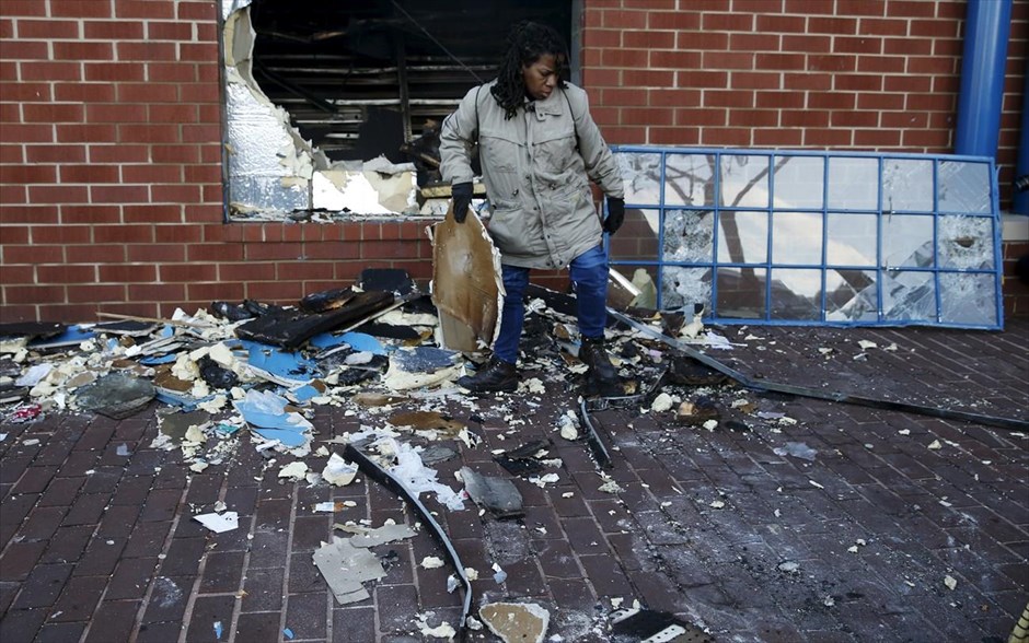 Βαλτιμόρη - επεισόδια. Γυναίκα καθαρίζει τις ζημιές που έχουν προκληθεί στο κατάστημά της.