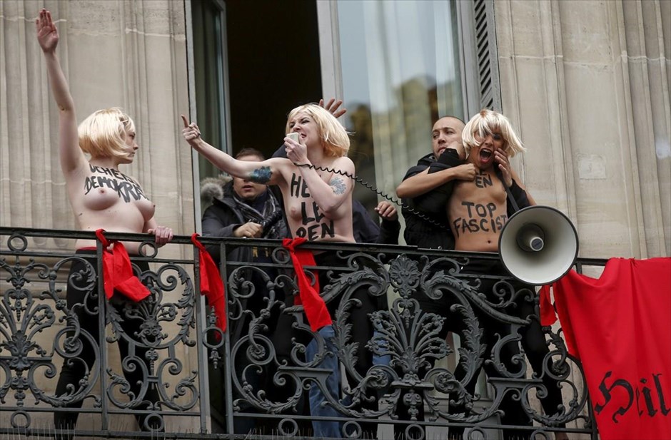 Γαλλία: Αντιμέτωπη με τις Femen η Μαρί Λεπέν. Τρείς ακτιβίστριες της φεμινιστικής οργάνωσης Femen, απομακρύνονται από άντρες ασφαλείας από ένα μπαλκόνι, όπου έχουν απλώσει μεγάλες κόκκινες σημαίες του Γ