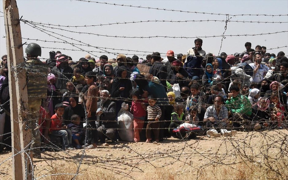 Πρόσφυγες από τη Συρία στην Τουρκία. Σύροι πρόσφυγες περιμένουν πίσω από το συνοριακό φράχτη, για να περάσουν στην Τουρκία, κοντά στη νοτιοανατολική πόλη Ακτσάκαλε, στην επαρχία Σανλιούρφα.