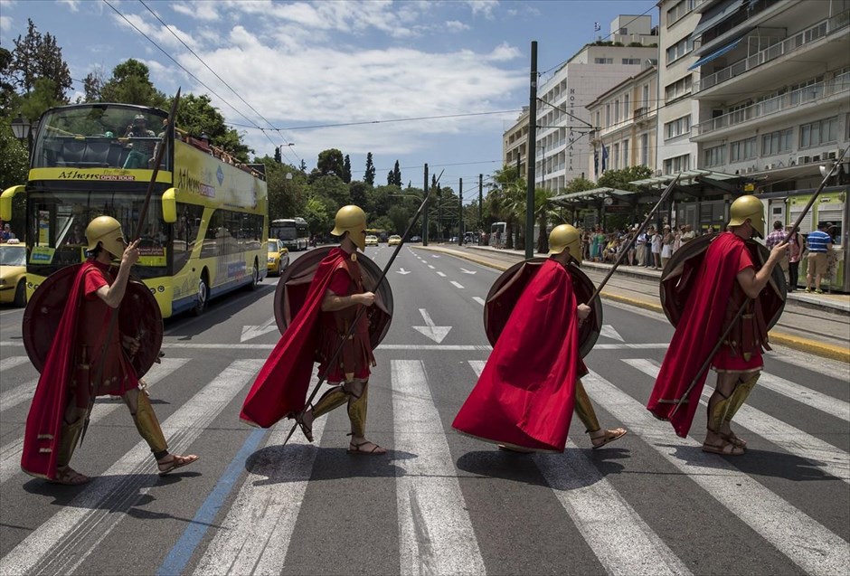 Σπαρτιάτες πολεμιστές στην πλατεία Συντάγματος. Άντρες με στολές Σπαρτιατών πολεμιστών διασχίζουν διάβαση πεζών στην πλατεία Συντάγματος, έχοντας, νωρίτερα, λάβει μέρος σε τελετή κατάθεσης στεφάνου στον Άγνωστο Στρατιώτη.