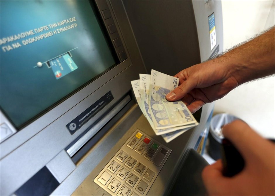 Στον ρυθμό του δημοψηφίσματος - Τράπεζες - ATM. Ένας άντρας κάνει ανάληψη από ATM. Τα καταστήματα των τραπεζών παραμένουν κλειστά από την περασμένη Δευτέρα, ενώ έχει τεθεί σε ισχύ ημερήσιο όριο αναλήψεων 60 ευρώ ανά κάρτα, μέσω αυτόματων ταμειολογιστικών μηχανών.