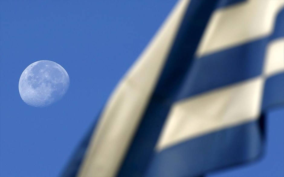 Ελλάδα - Κρίση - Οικονομία - Σημαία. Το φεγγάρι, όπως διακρίνεται νωρίς το πρωί από αυλή δημοτικού σχολείου που λειτουργεί ως εκλογικό τμήμα, στην Αθήνα.&nbsp;