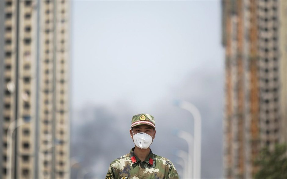 Κίνα: Δεκάδες νεκροί από ισχυρές εκρήξεις στην πόλη Τιαντζίν 5. Ένας αστυνομικός φορώντας μάσκα, μπλοκάρει τον δρόμο που οδηγεί σε κατοικημένη περιοχή που εκκενώθηκε λόγω των εκρήξεων.