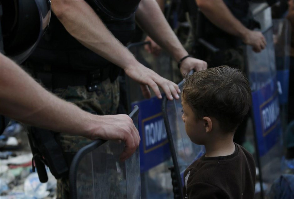 Προσφυγικό - μετανάστες - πρόσφυγες - ΠΓΔΜ. Ένας παιδί από τη Συρία στέκεται μπροστά από την αστυνομία της ΠΓΔΜ, η οποία φρουρεί τα σύνορα.