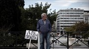 Ενας πολίτης βρίσκεται στην πλατεία Συντάγματος αναμένοντας την απογευματινή πορεία στην Αθήνα. ...