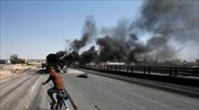 Ενα αγόρι κάνει ποδήλατό καθώς καπνοί υψώνονται πάνω από το Χαλέπι στη ...