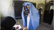 Μια Αφγανή δείχνει το πρόσωπο της στην εκλογική αντιπρόσωπο πριν ψηφίσει για ...